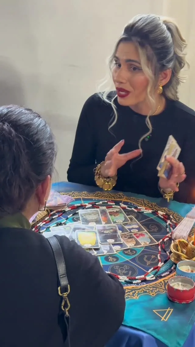 Sarah atendendo com tarô sobre uma mesa na Expo Bruxas Curitiba