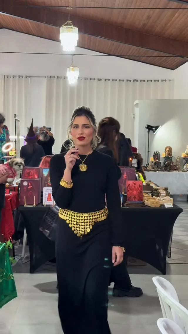 Sarah de preto e dourado entre os estandes da Expo Bruxas