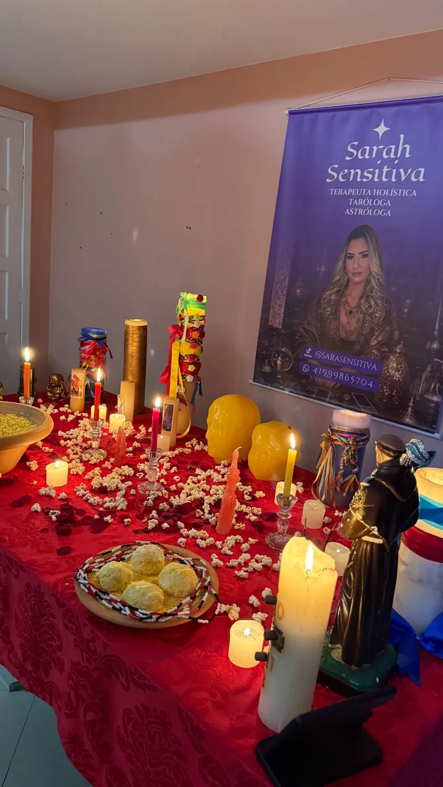 Mesa vermelha com velas e o banner da Sarah Sensitiva